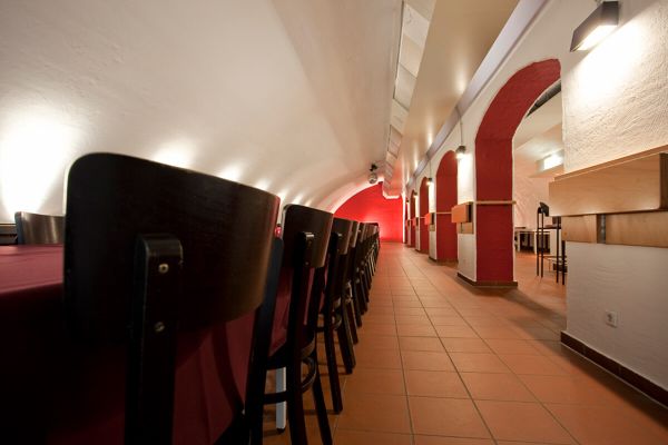 Perspektive in den Jazzkeller fotografiert. Links sind Stühle und rechts der bogenförmige Durchgang zur Bar